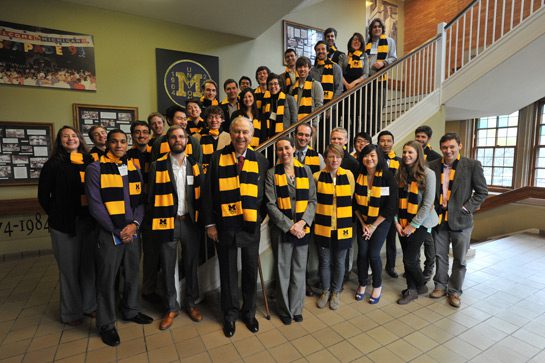 A group of 35 Taubman Scholars wearing maize and blue scarves standing along a stairwell.