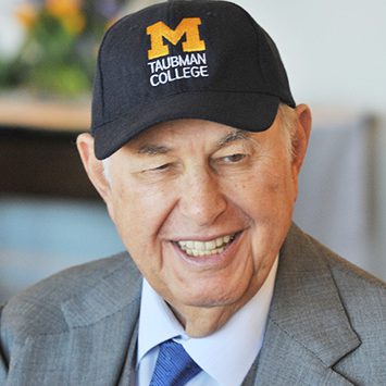 Portrait of A Alfred Taubman wearing a blue U-M Taubman College hat.