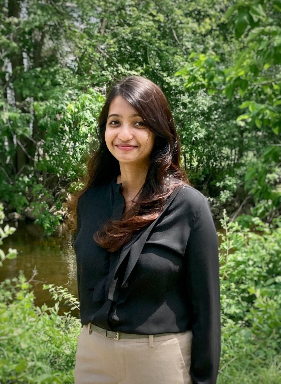 a photo of Deepthi Bathala standing in front of green foliage