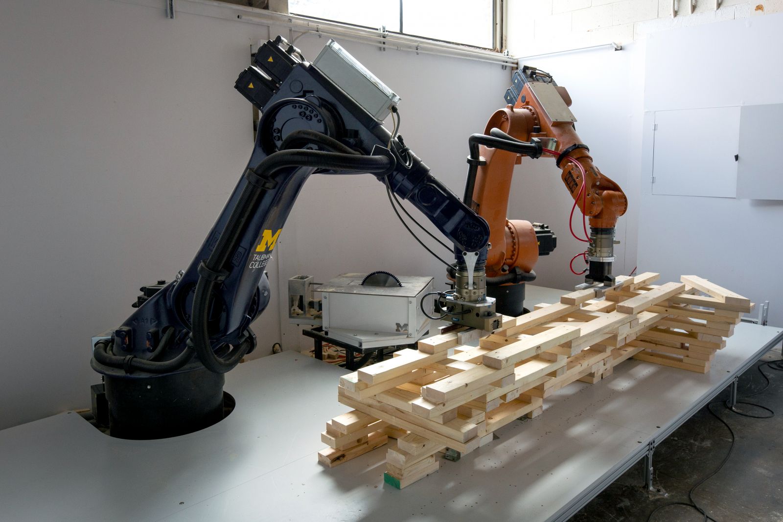 Image of two robotic arms assembling a wooden structure.