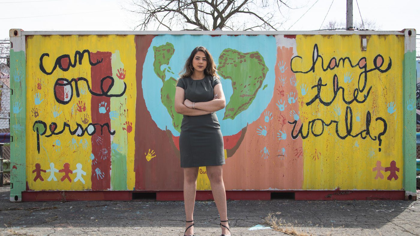 Image of a woman standing in front of a shipping container painted with images of earth and messages of 