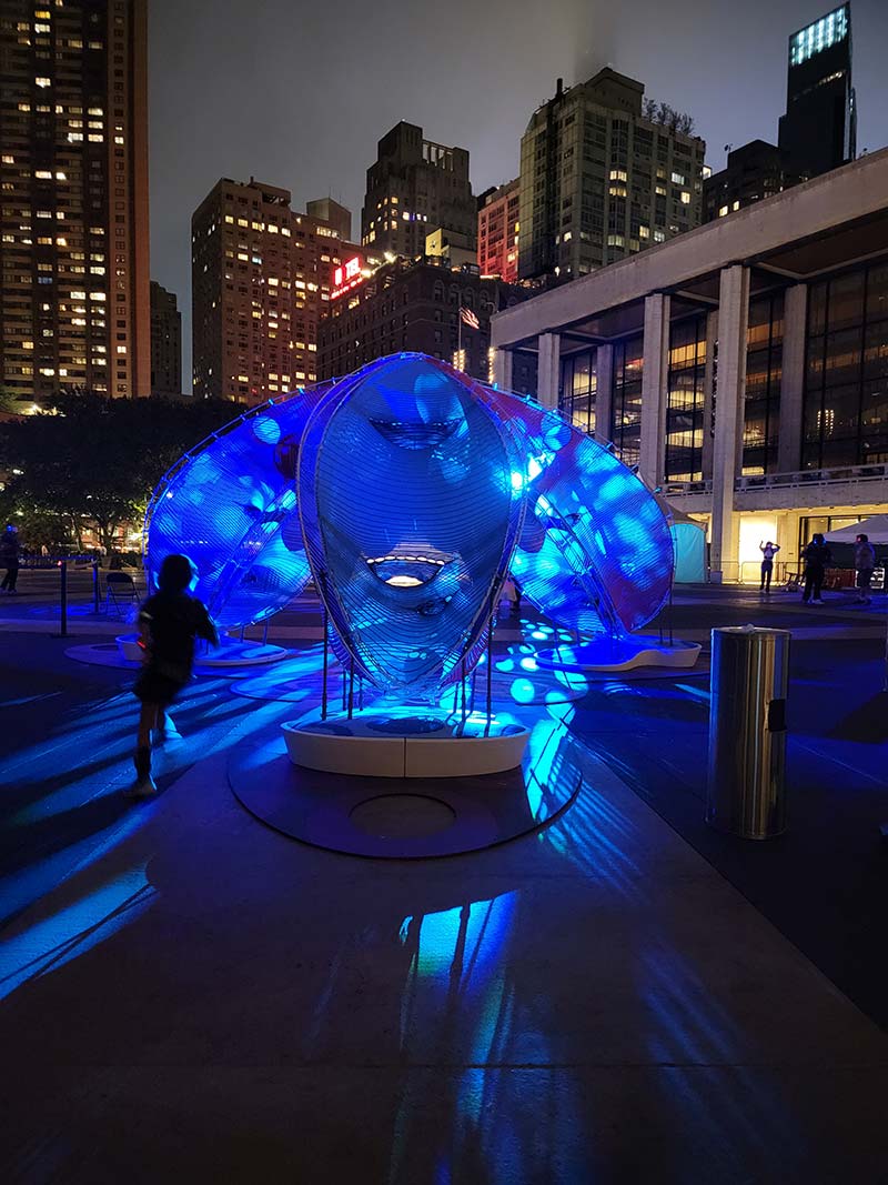 A large umbrella-like structure at night lit in blue light.