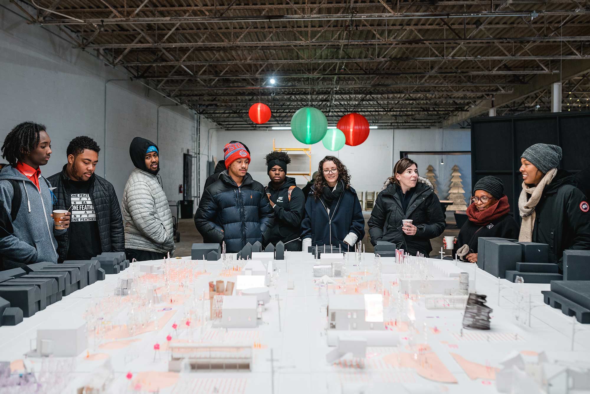 A group of people looking over an architectural model of a neighborhood
