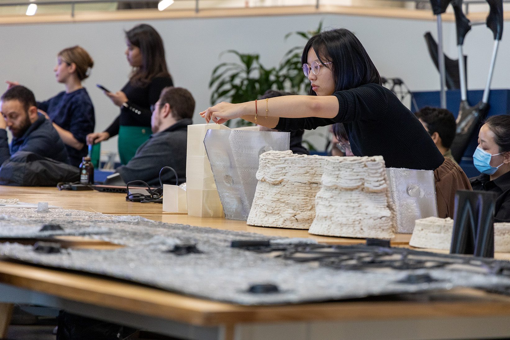 A student makes final adjustments to 3D printed pieces of work during a studio review.