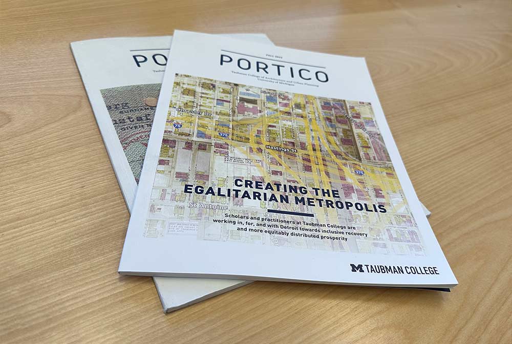 Two copies of the Portico magazine on a light wood tabletop.