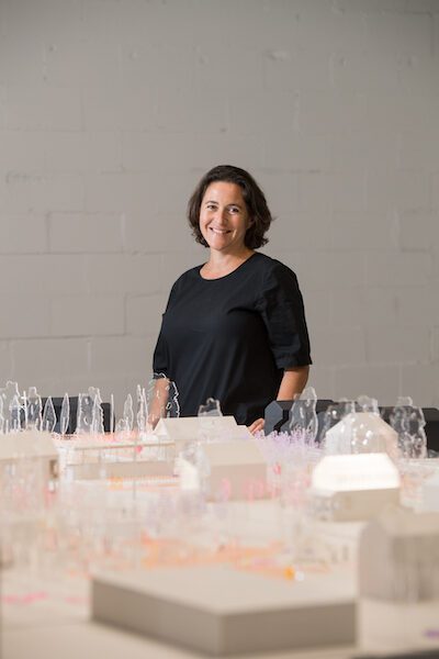 Anya Sirota stands in front of a table full of 3D models