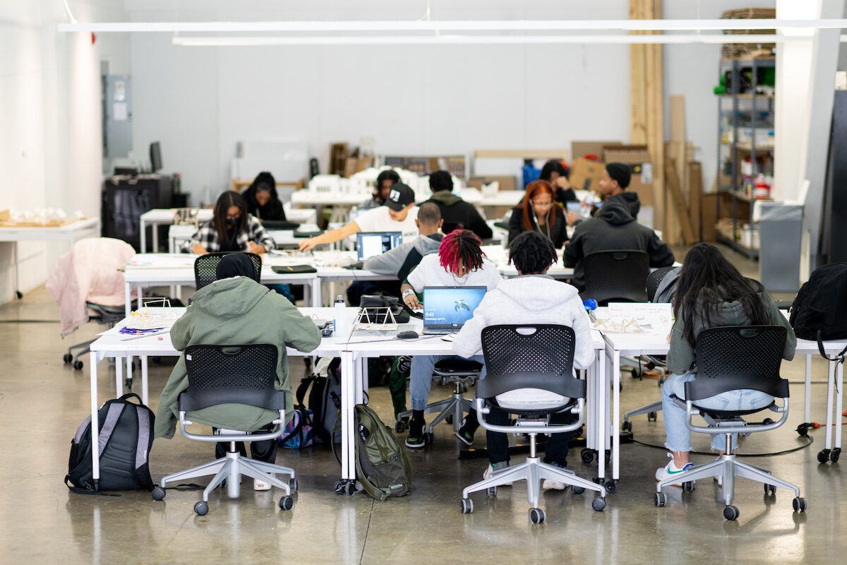 Students working on projects at a series of tables that have been pushed together