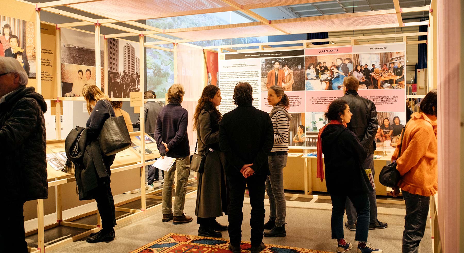 A group of people viewing and discussing an exhibit about The Gift: Stories of Generosity and Violence in Architecture