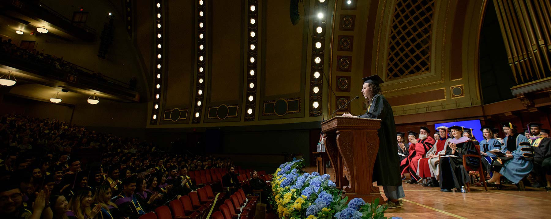 A speaker at commencement addressing the auditorium of graduates.