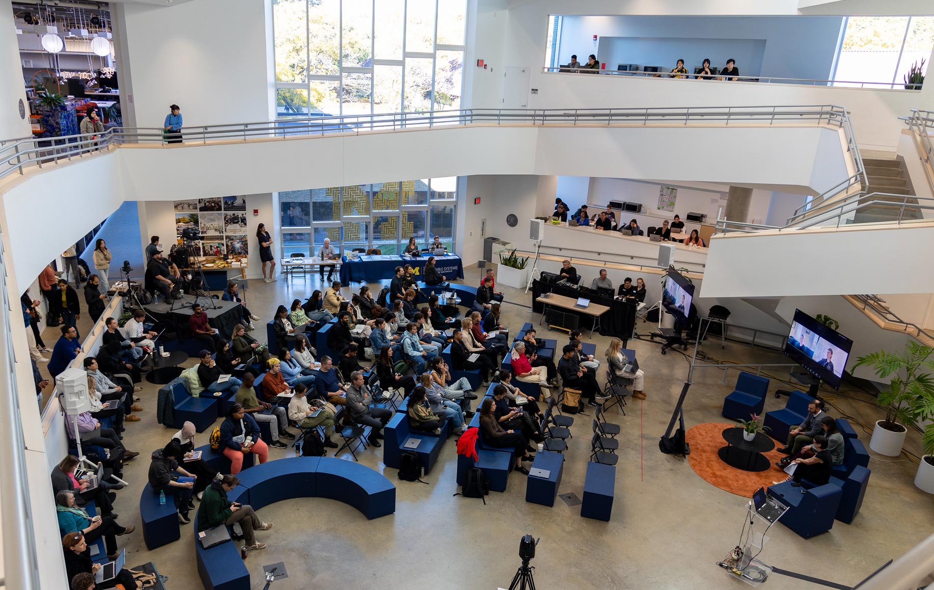 A crowd of people watch several panel speakers at the Climate Futures Symposium