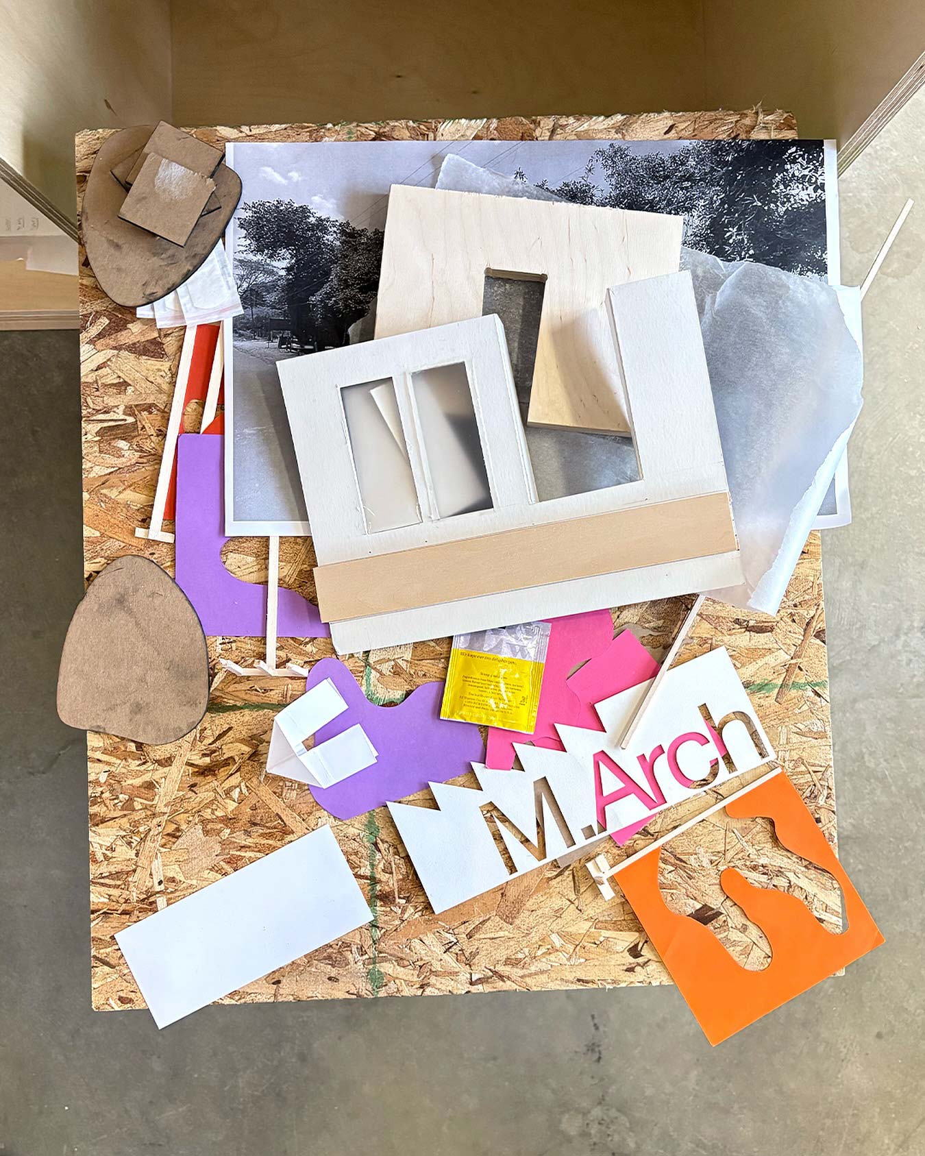 A tabletop with various scraps of paper and design pieces along with the M.Arch logo.