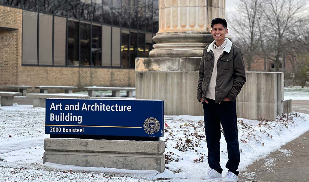 Kevin Gonzalez Ramirez standing next to the sign for the Art and Architecture Building