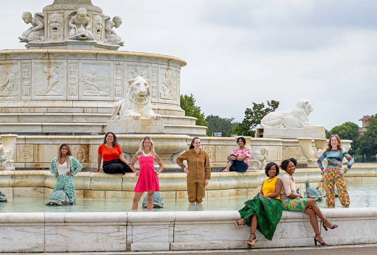 Eight women standing in and around a fountain. Photo by John D'Angelo