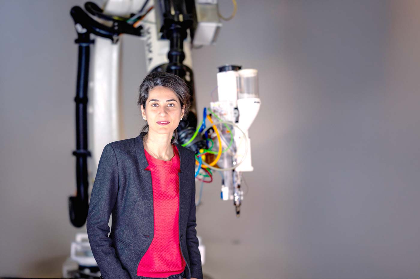 Dr Mania Aghaei Meibodi stands in front of a robotic printer