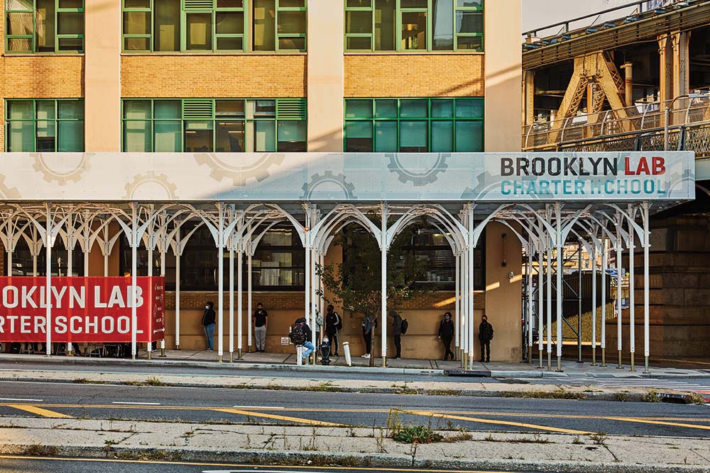 The entrance of Brooklyn Lab Charter School with people standing under a white arched canopy.