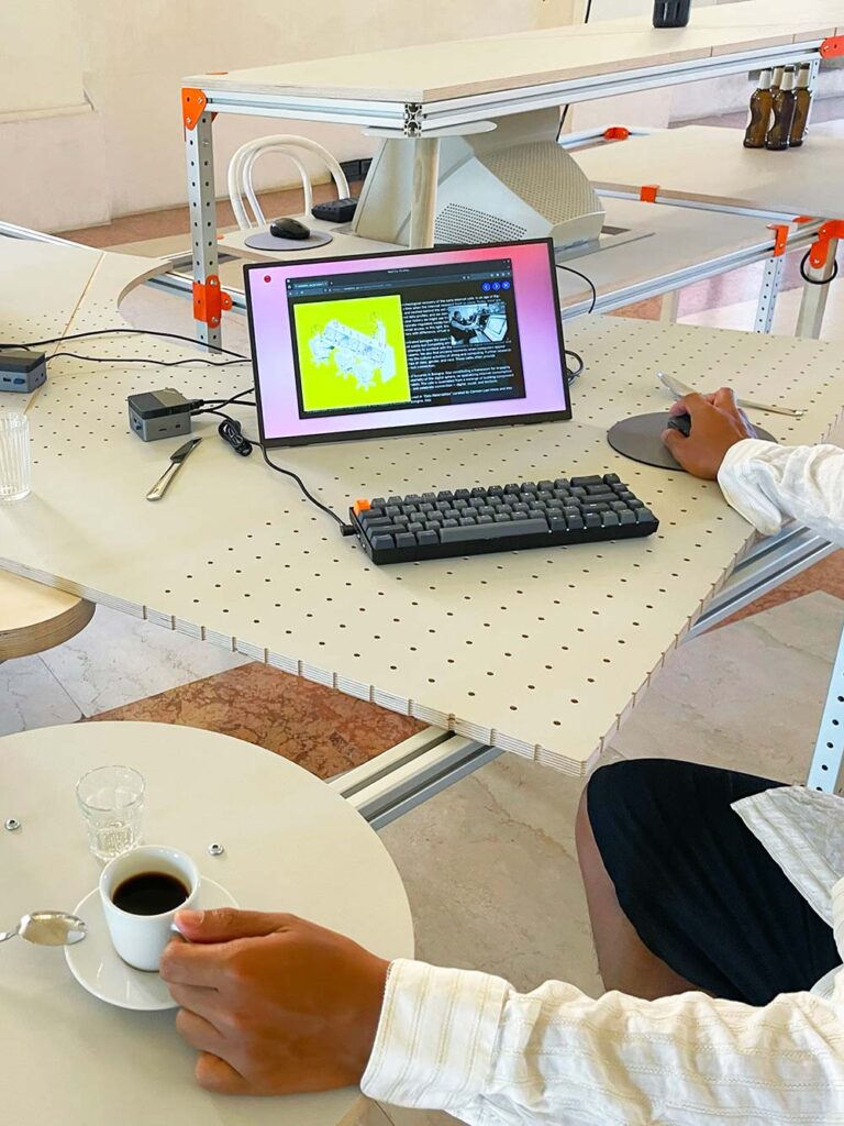 A monitor sitting on a table with a keyboard and a user using the mouse to browse a website