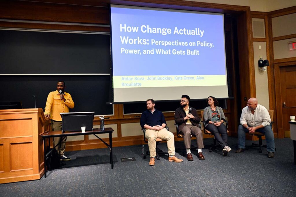 A group of people sitting in chairs on a panel about "How Change Actually Works"