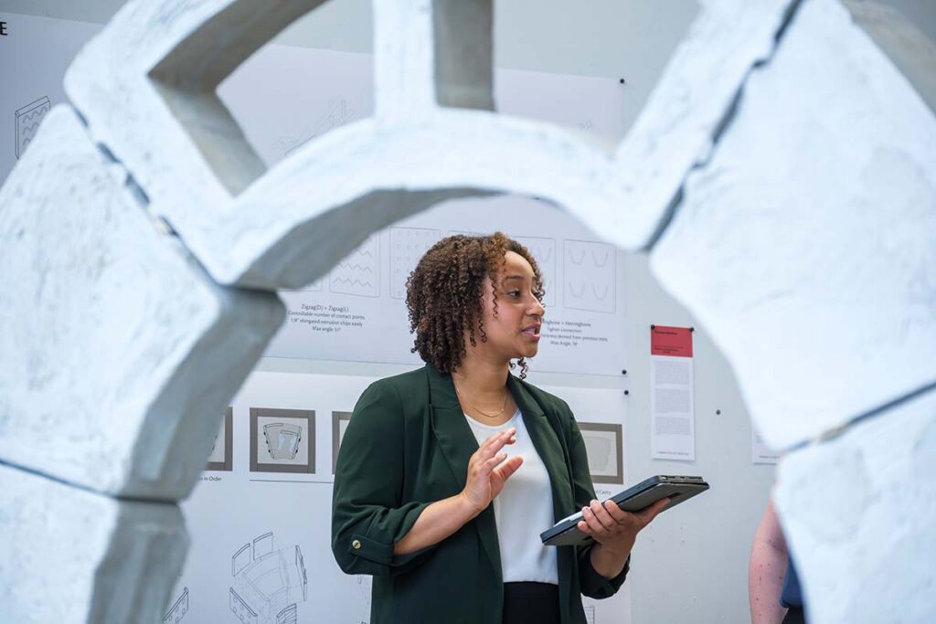 Cayla Ellis presenting as viewed through a concrete arched structure
