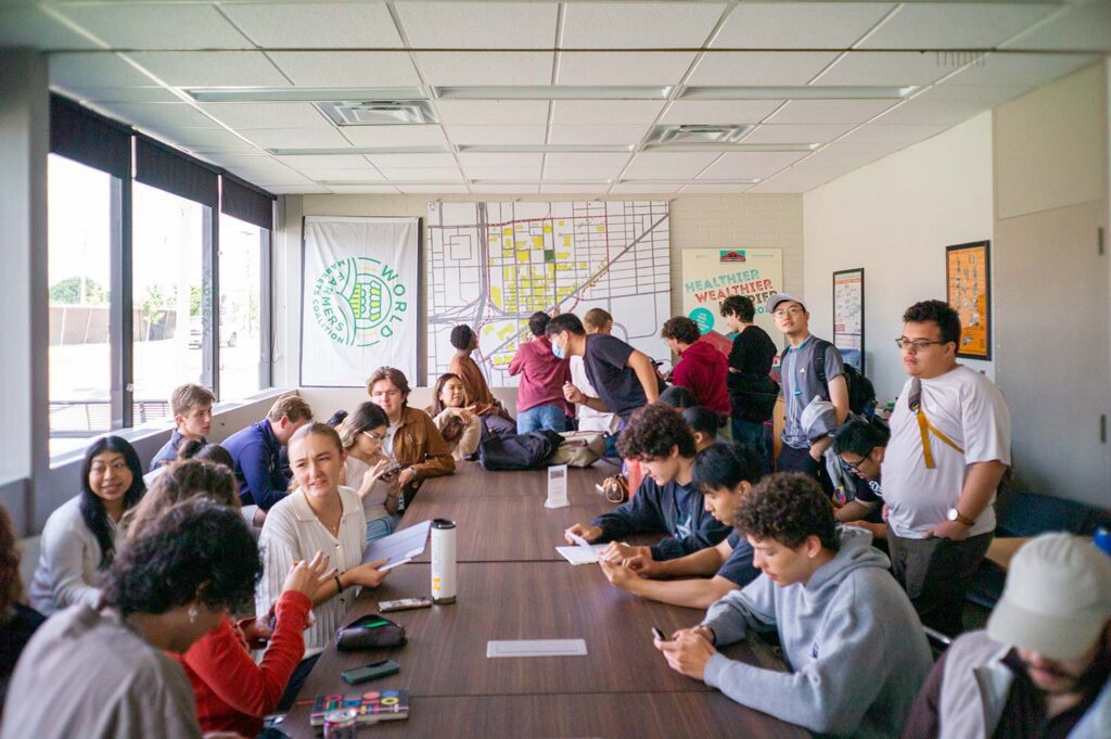 A group of students crowded around a table in various stages of discussion