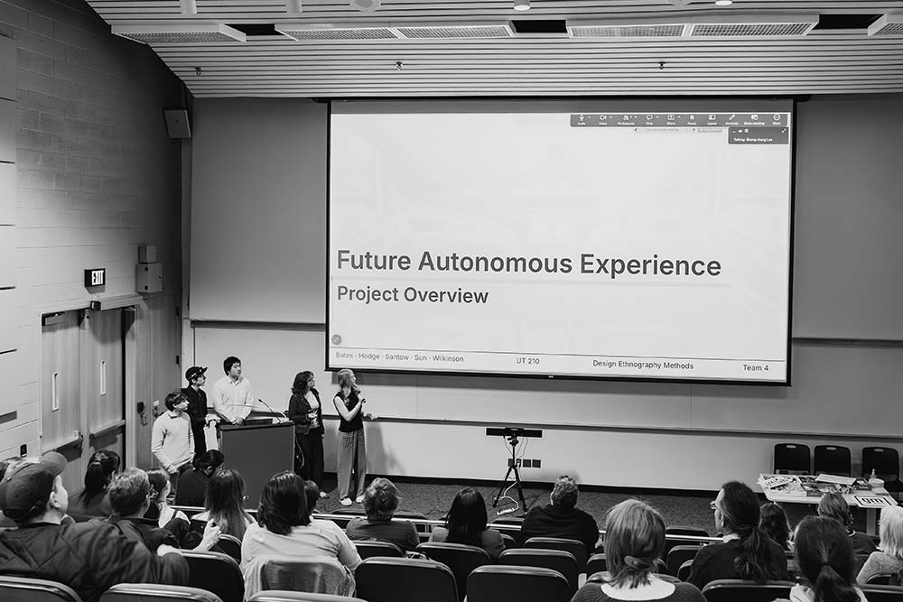 Students present “Future Autonomous Experience: Project Overview” to an audience in a lecture hall.