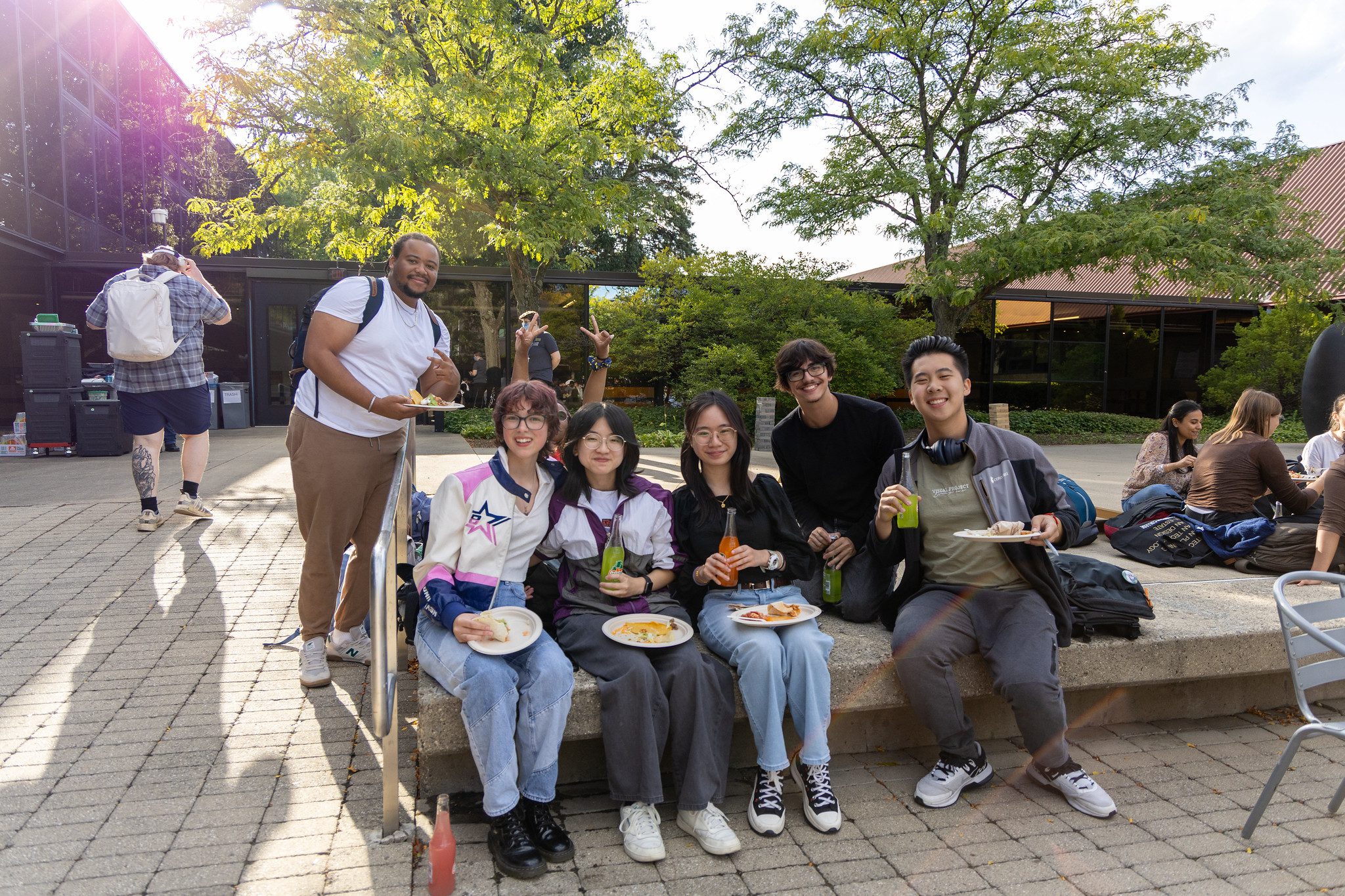 A diverse group of students eating food outside posing for a photo