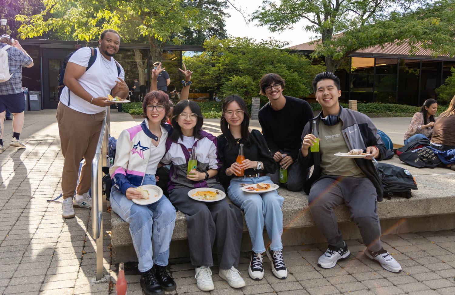 A diverse group of students eating food outside posing for a photo