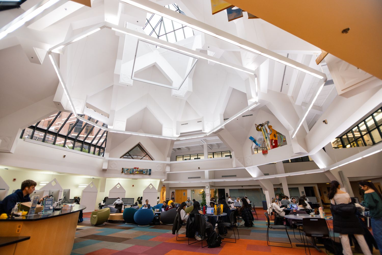 wide low angle view of a building interior with students studying at tables