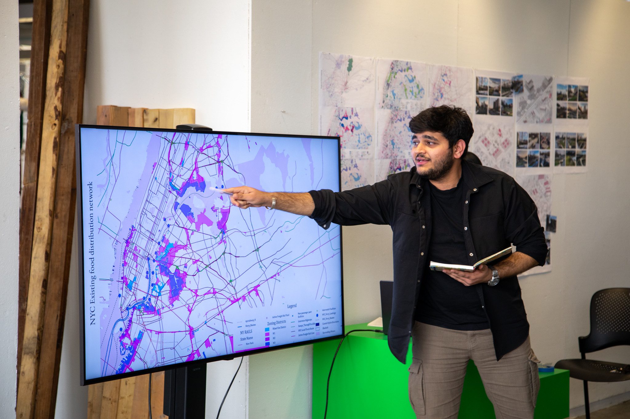 A student presents in front of a large tv screen with a map on it