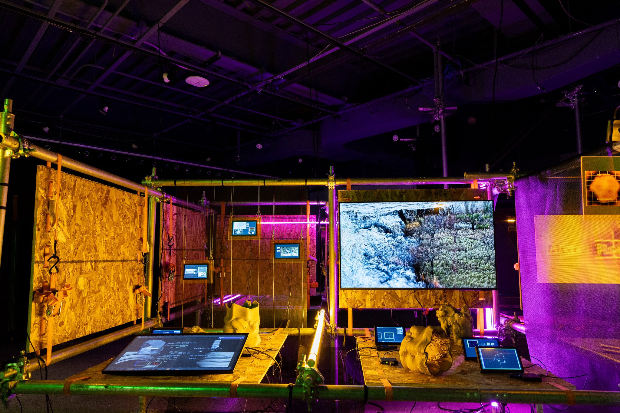 a dark room illuminated by yellow, purple and blue colored lights and screens
